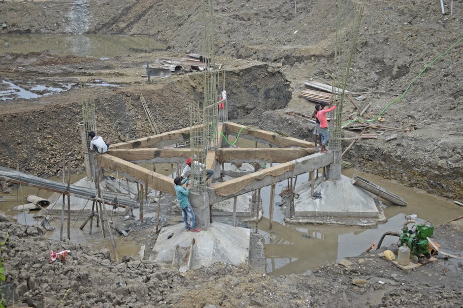 Workers constructing a building foundation with rebar and wooden supports outdoors